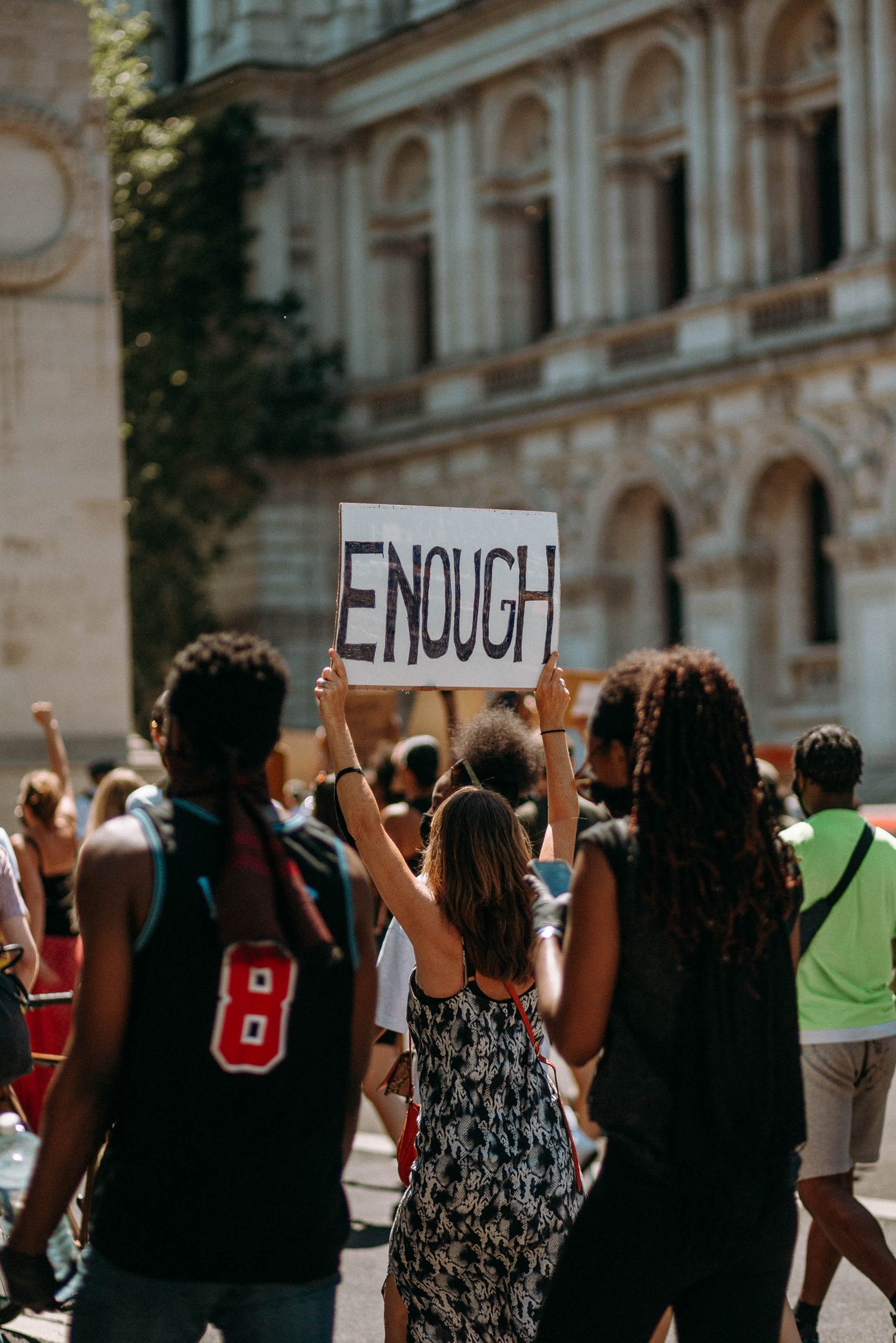 woman in march holding sign that reads 'Enough' (link to file)