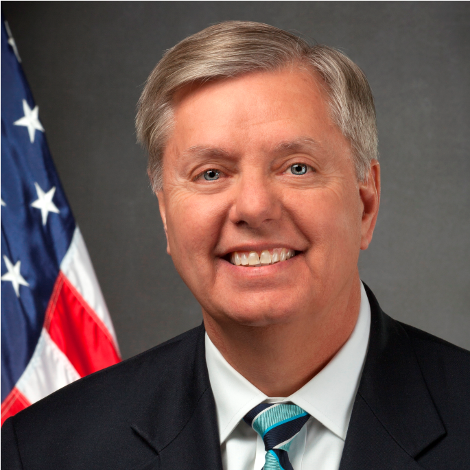 man in a suit and tie, with an American flag in background