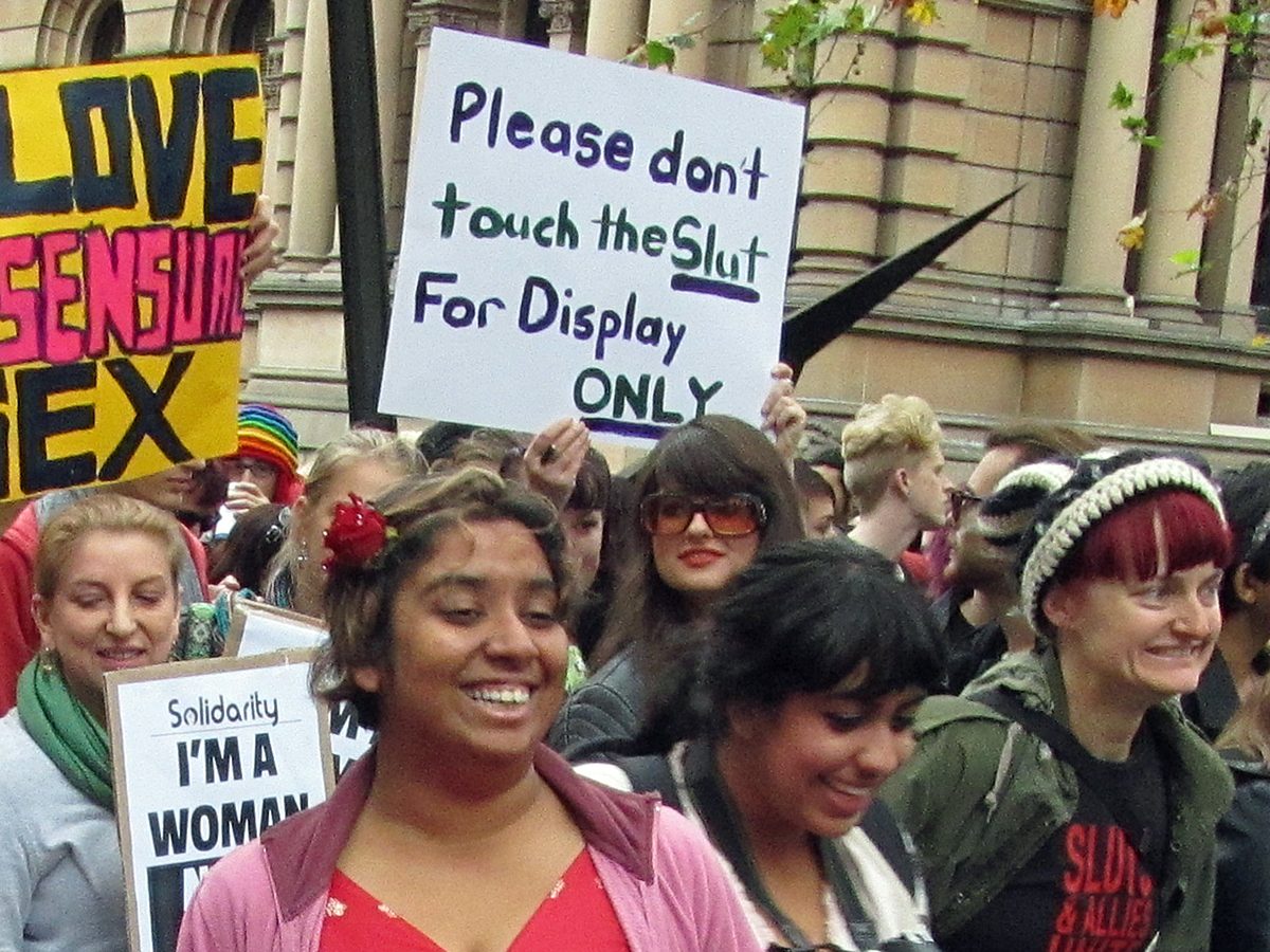 A crowd of women holding signs, one of which reads ‘Please don’t touch the Slut, For Display ONLY’”