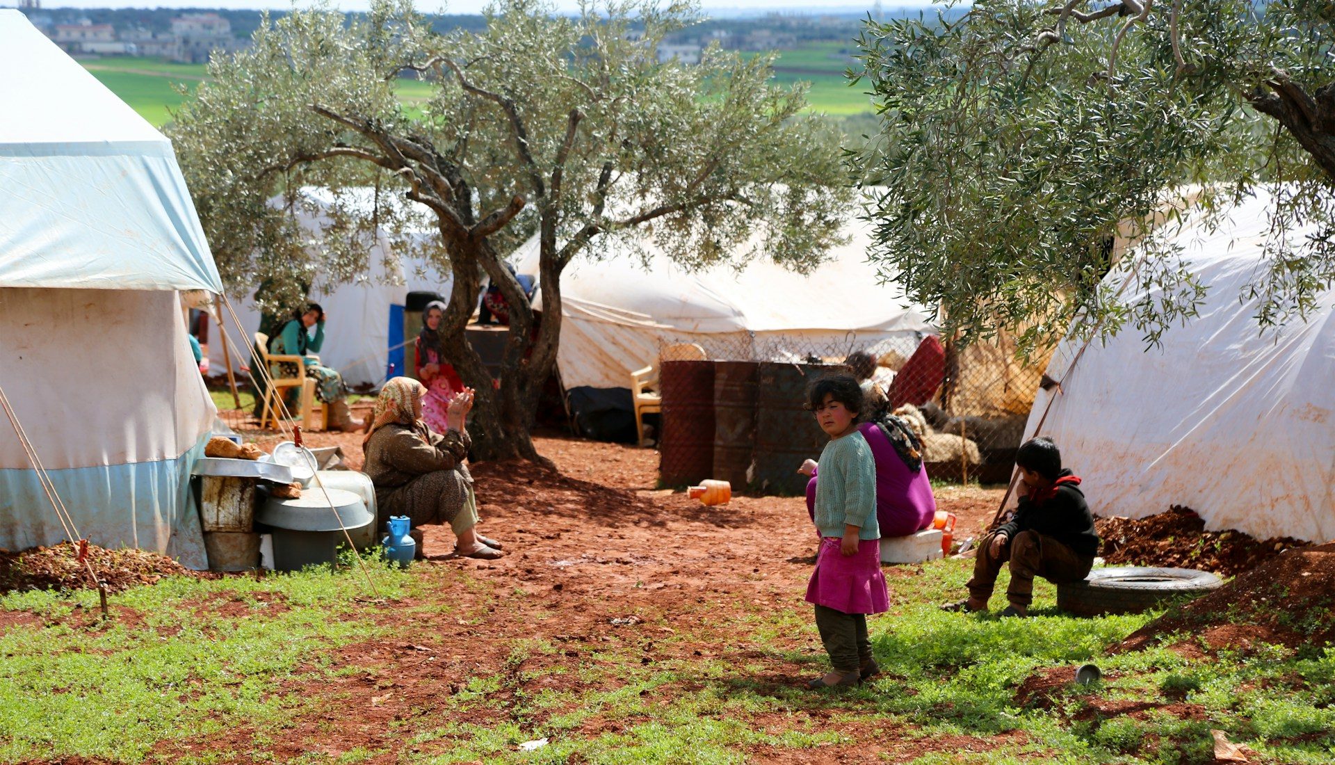 A group of people standing in a field next to tents